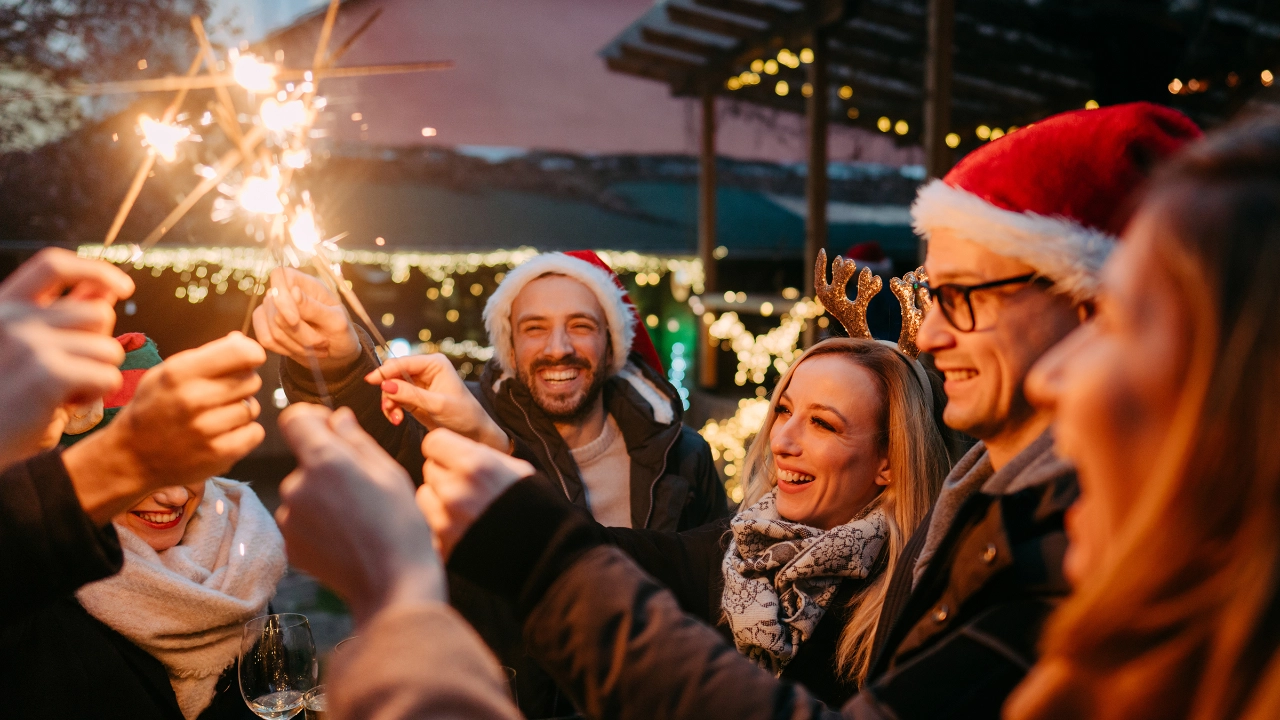 Mehrere Menschen feiern ausgelassen auf einem Weihnachtsmarkt.