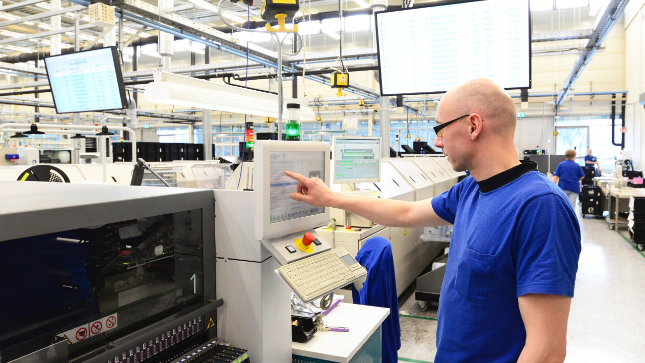 Ein Beschäftigter bedient den Monitor einer Maschine in einer High-Tech-Fabrik.